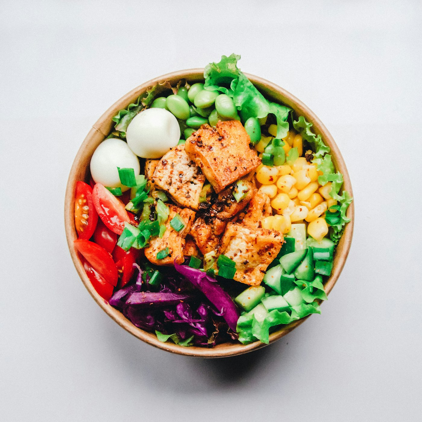 Bowl con hojas verdes, huevo, elote, edamame y tofu