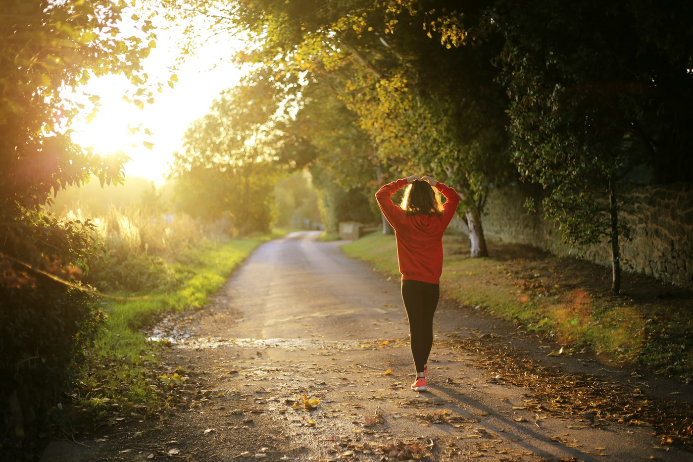 Mujer camina por un sendero arbolado al atardecer
